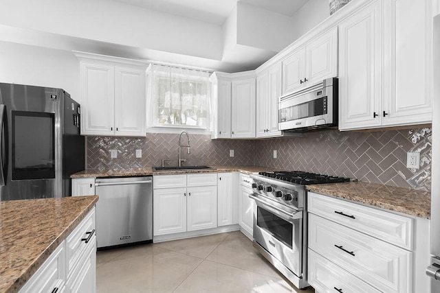 kitchen with sink, dark stone counters, white cabinets, and appliances with stainless steel finishes