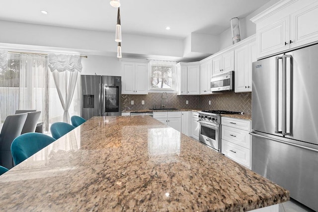 kitchen with pendant lighting, high quality appliances, white cabinetry, sink, and light stone counters