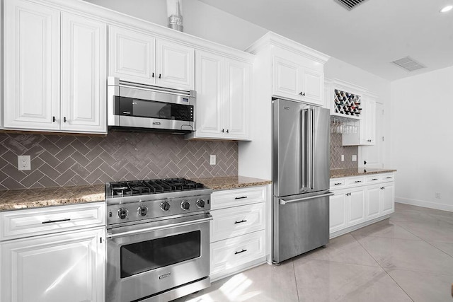 kitchen featuring white cabinetry, high quality appliances, light stone countertops, and tasteful backsplash