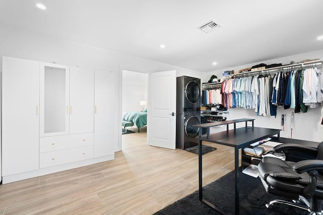 walk in closet featuring light hardwood / wood-style flooring and stacked washer / dryer