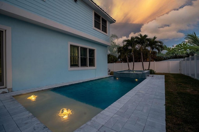 pool at dusk featuring a patio area and an in ground hot tub