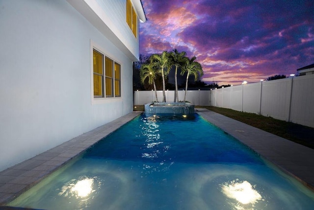 pool at dusk with an in ground hot tub