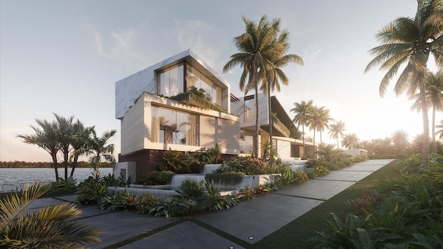 property exterior at dusk with a balcony and a water view