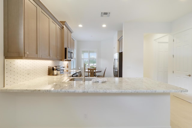 11263 SW Visconti Way, Port Saint Lucie, FL 34986 - kitchen with stainless steel appliances, backsplash, a peninsula, light stone counters, and recessed lighting