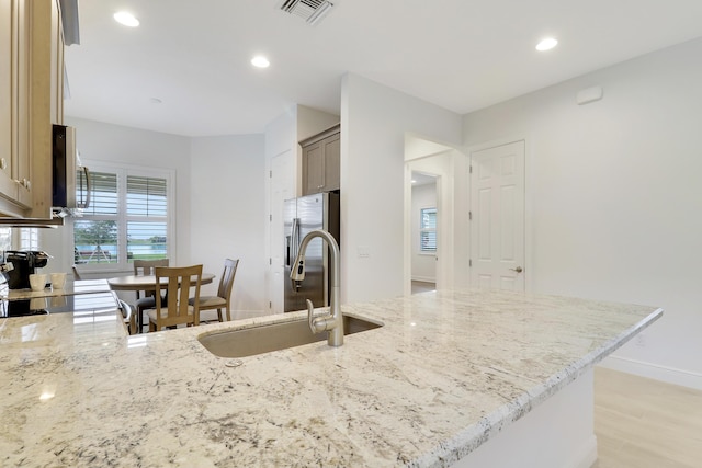 kitchen with sink, light stone countertops, range, and light wood-type flooring