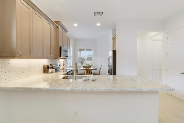 11263 SW Visconti Way, Port Saint Lucie, FL 34986 - kitchen with stainless steel appliances, a peninsula, tasteful backsplash, light stone countertops, and recessed lighting