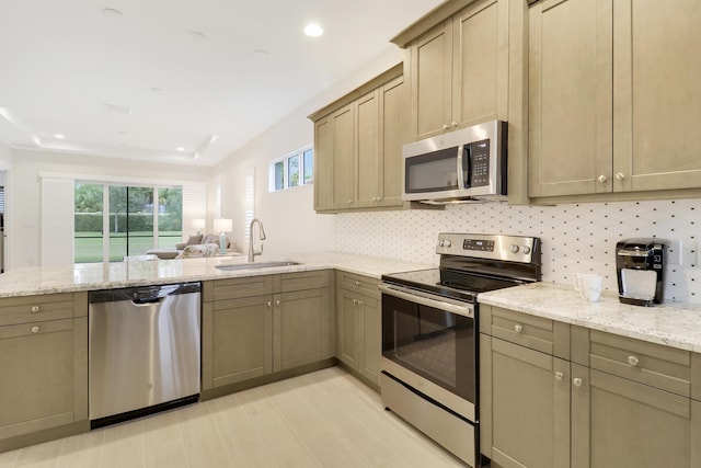 kitchen featuring sink, backsplash, light stone counters, kitchen peninsula, and stainless steel appliances