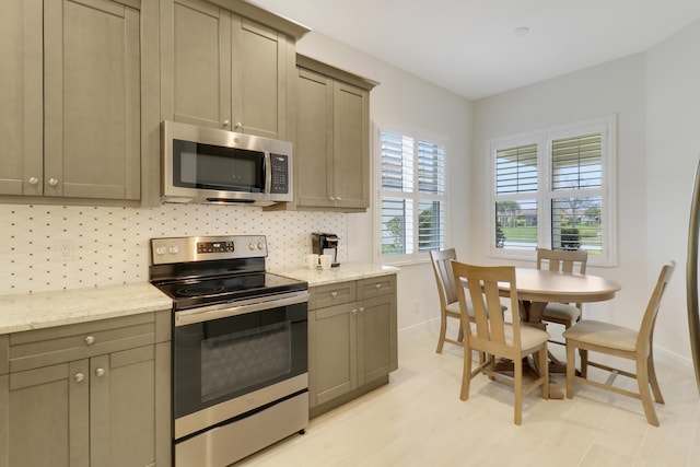 kitchen featuring appliances with stainless steel finishes, backsplash, and light stone counters