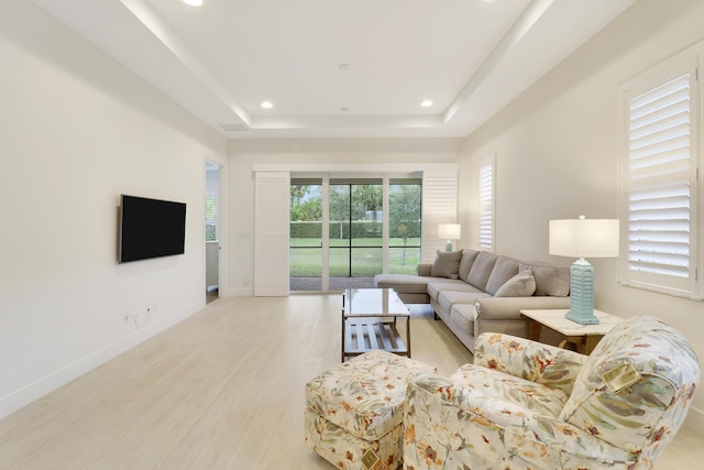 living room with a tray ceiling and light wood-type flooring