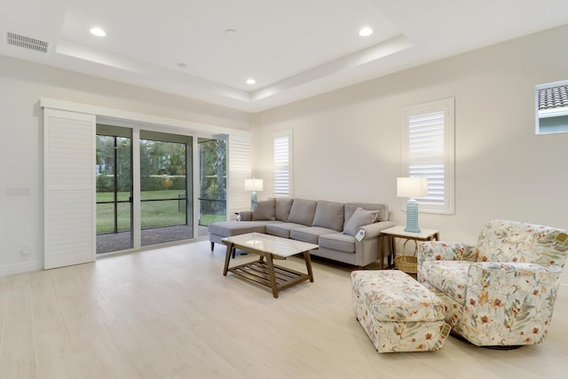 living room featuring a tray ceiling and light hardwood / wood-style flooring