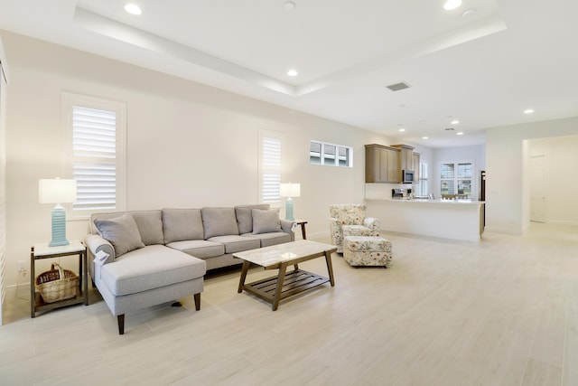 living room with light hardwood / wood-style flooring and a tray ceiling