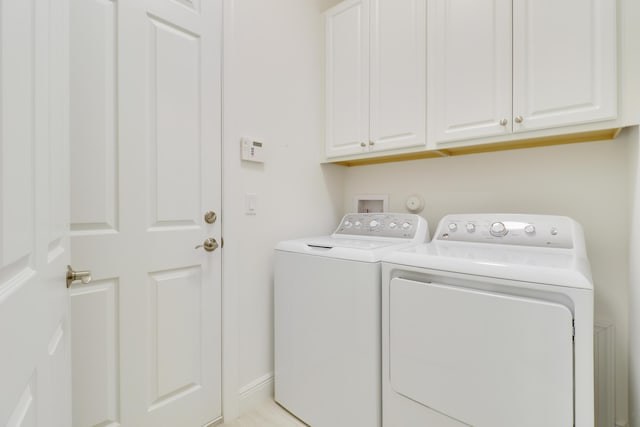 clothes washing area with cabinets and independent washer and dryer