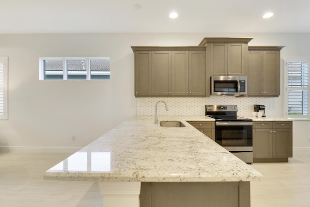 kitchen featuring tasteful backsplash, sink, stainless steel appliances, and light stone countertops