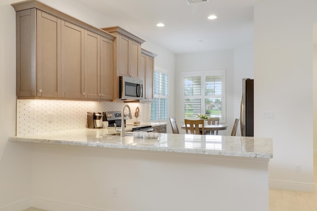 11263 SW Visconti Way, Port Saint Lucie, FL 34986 - kitchen featuring stainless steel appliances, a peninsula, light stone countertops, backsplash, and recessed lighting