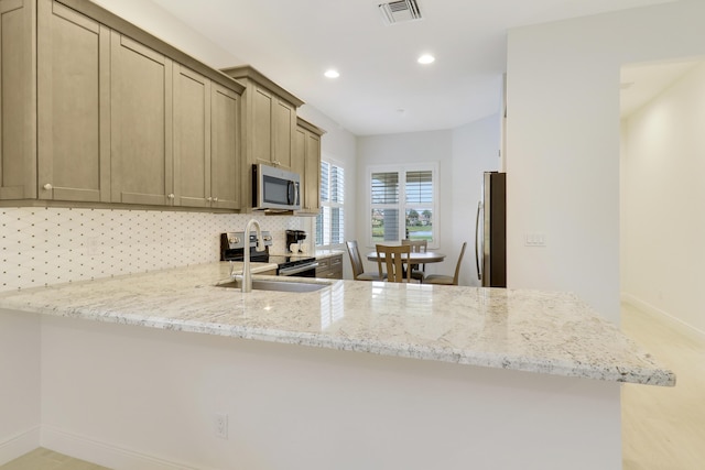 kitchen featuring stainless steel appliances, light stone countertops, backsplash, and kitchen peninsula