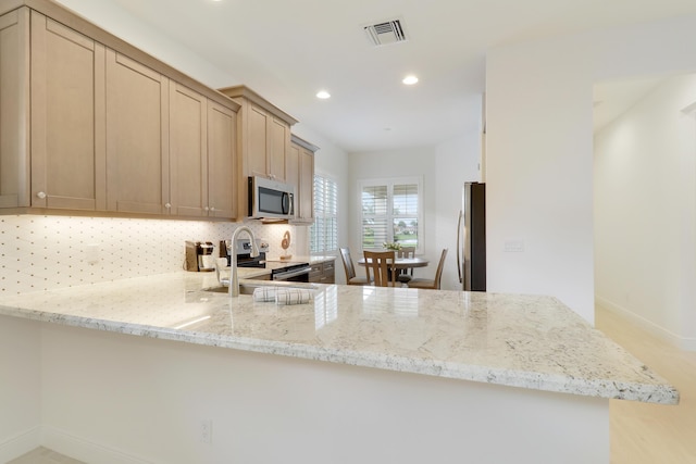 11263 SW Visconti Way, Port Saint Lucie, FL 34986 - kitchen with appliances with stainless steel finishes, a peninsula, recessed lighting, decorative backsplash, and light stone counters