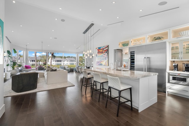 kitchen featuring light stone countertops, a spacious island, decorative light fixtures, vaulted ceiling, and a breakfast bar area