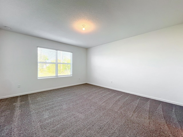 unfurnished room with dark colored carpet and a textured ceiling