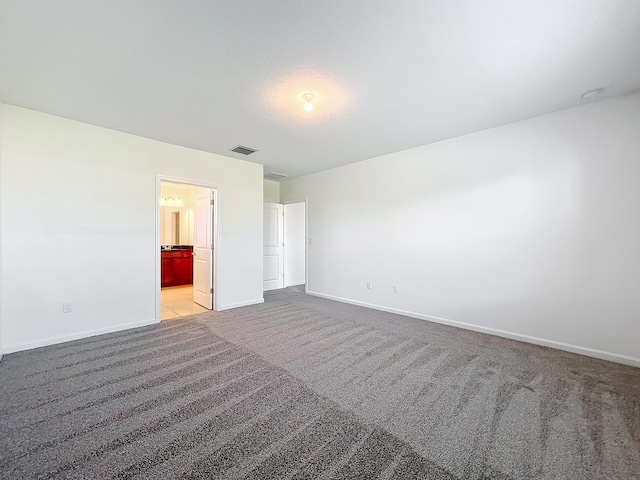 unfurnished bedroom featuring light colored carpet and ensuite bath