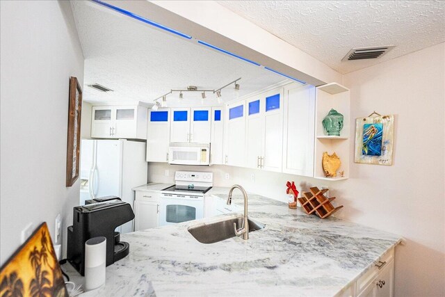 kitchen with a peninsula, white dishwasher, a textured ceiling, white cabinetry, and a sink