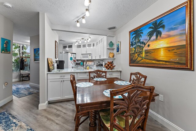 dining area with rail lighting, baseboards, marble finish floor, and a textured ceiling