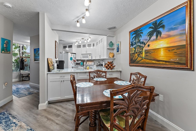 1806 SE Hideaway Cir Unit 1806, Port Saint Lucie, FL 34952 - dining room with a textured ceiling, light wood finished floors, track lighting, and baseboards