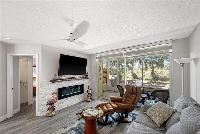 living area with visible vents, ceiling fan, a textured ceiling, wood finished floors, and baseboards