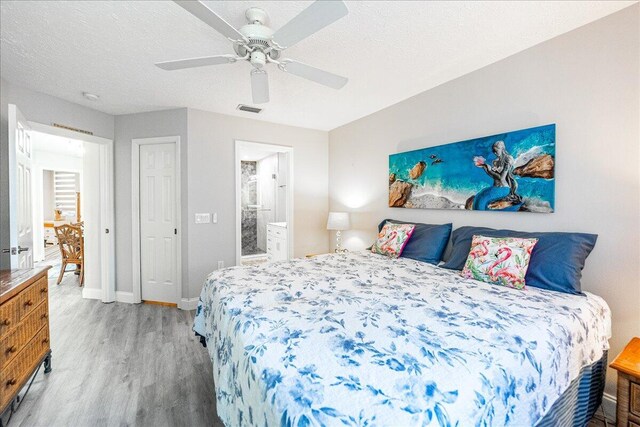 1806 SE Hideaway Cir Unit 1806, Port Saint Lucie, FL 34952 - bedroom featuring wood finished floors, baseboards, ceiling fan, ensuite bath, and a textured ceiling