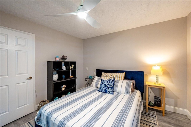 bedroom featuring a textured ceiling, ceiling fan, wood finished floors, and baseboards