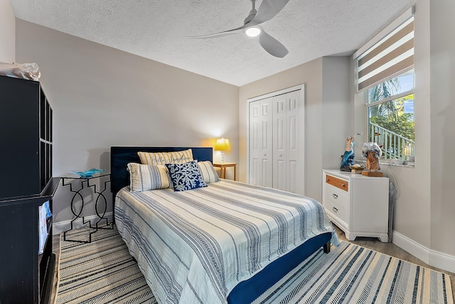 bedroom with a closet, a ceiling fan, a textured ceiling, wood finished floors, and baseboards