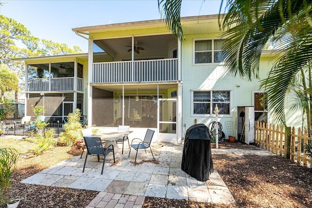 rear view of house featuring a balcony, a sunroom, ceiling fan, fence, and a patio area