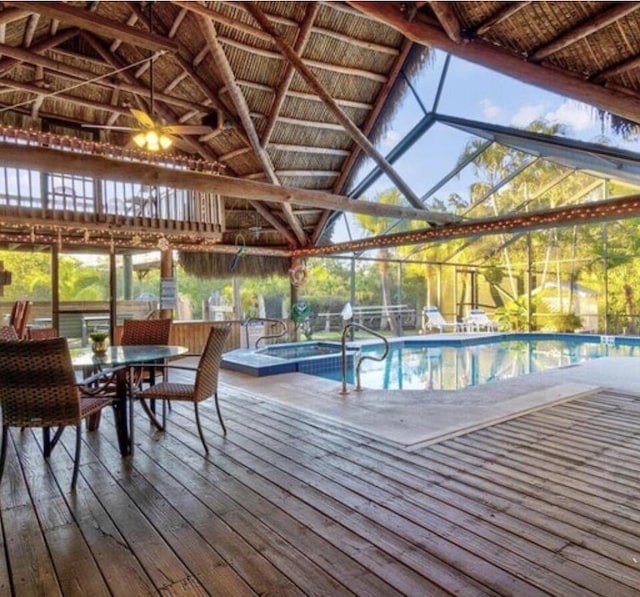 outdoor pool with glass enclosure, a hot tub, and a wooden deck