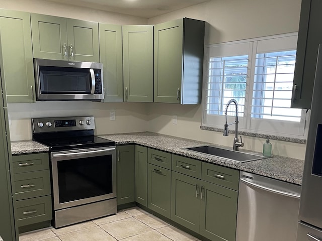 kitchen with green cabinetry, appliances with stainless steel finishes, sink, and light tile patterned floors