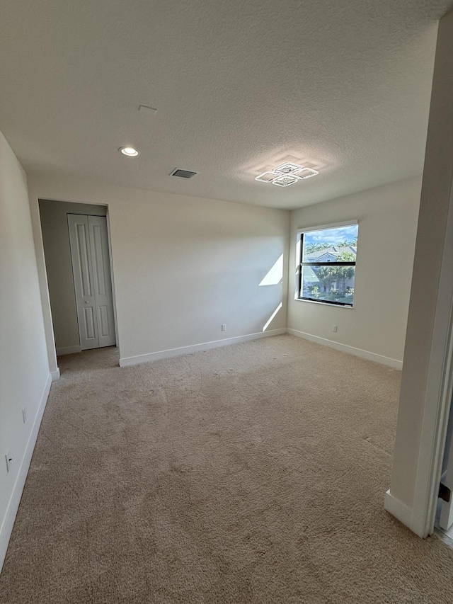 carpeted empty room with a textured ceiling