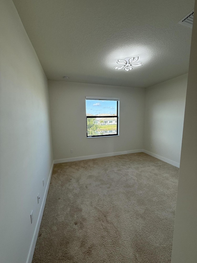 carpeted empty room featuring a textured ceiling