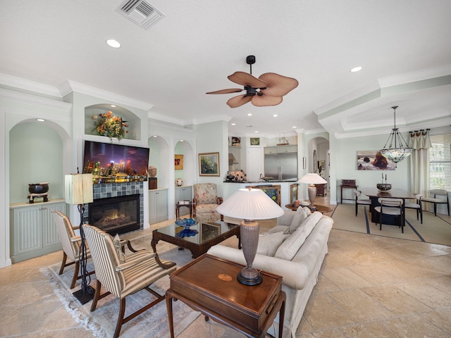 living room featuring a tiled fireplace, crown molding, and ceiling fan