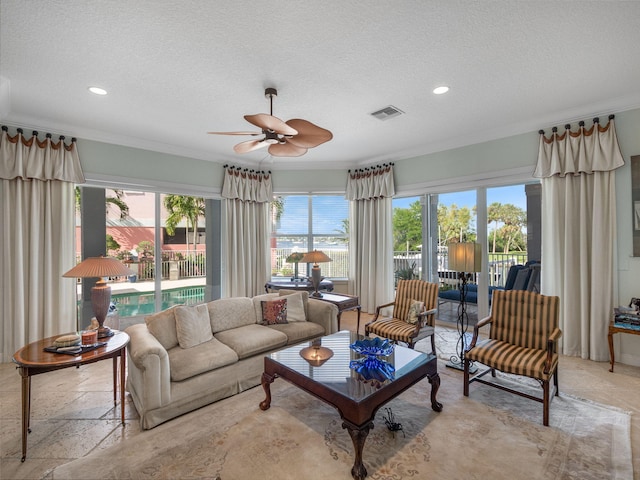 living room with ceiling fan, ornamental molding, and a textured ceiling