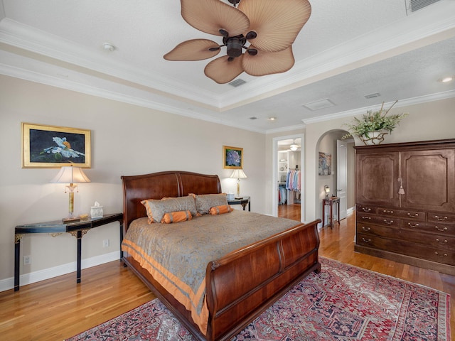 bedroom featuring crown molding, ceiling fan, a raised ceiling, and light wood-type flooring