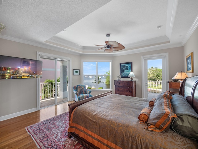 bedroom with hardwood / wood-style flooring, ornamental molding, access to exterior, a raised ceiling, and a textured ceiling