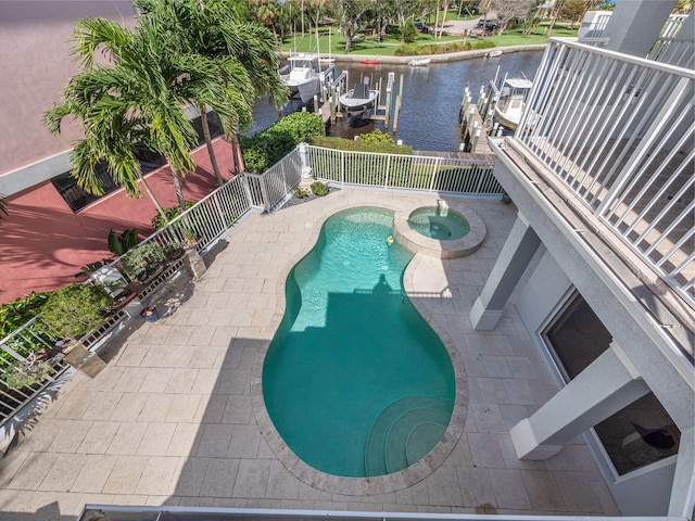 view of swimming pool featuring an in ground hot tub, a water view, a dock, and a patio area