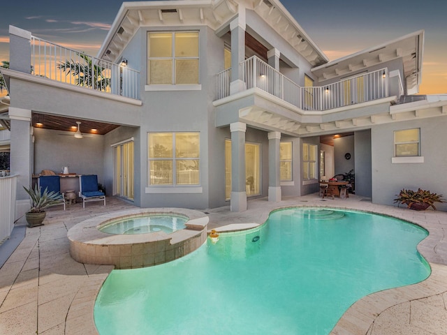 pool at dusk with an in ground hot tub, ceiling fan, and a patio