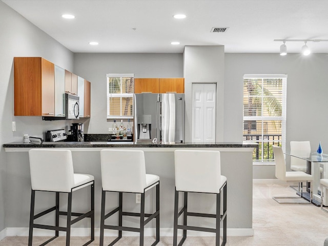 kitchen featuring rail lighting, stainless steel fridge, light carpet, and a wealth of natural light