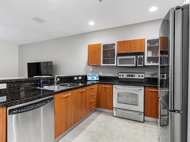 kitchen featuring dark stone countertops, light tile patterned floors, sink, and appliances with stainless steel finishes