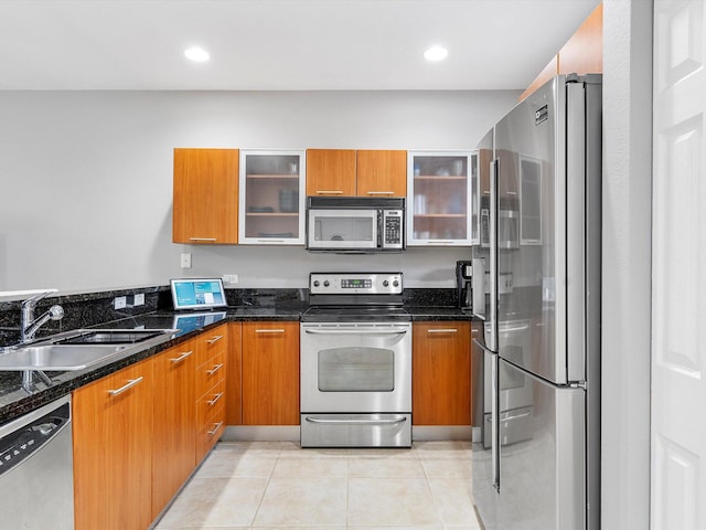 kitchen with sink, light tile patterned floors, dark stone counters, and appliances with stainless steel finishes