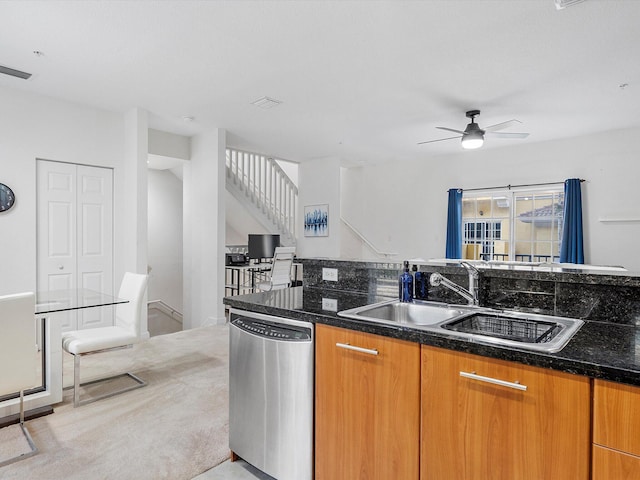 kitchen with ceiling fan, sink, stainless steel dishwasher, dark stone counters, and light colored carpet