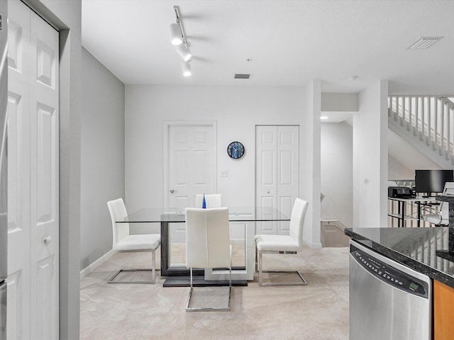 carpeted dining area featuring rail lighting