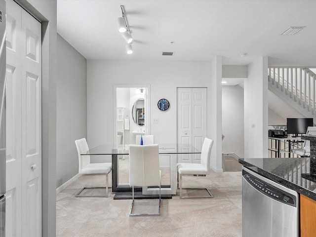 dining room with light carpet and track lighting