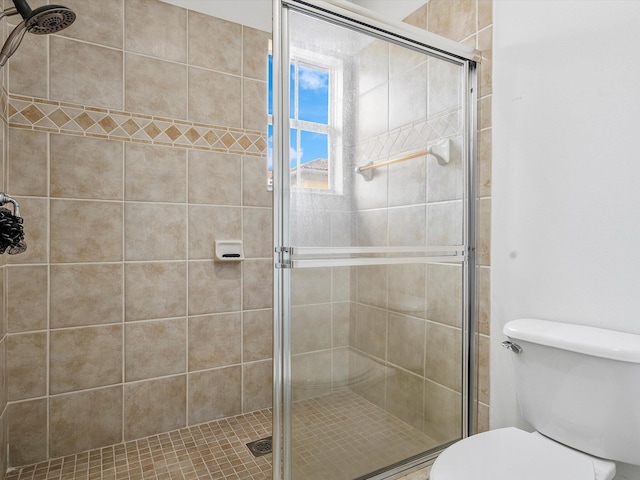 bathroom featuring toilet and a shower with door