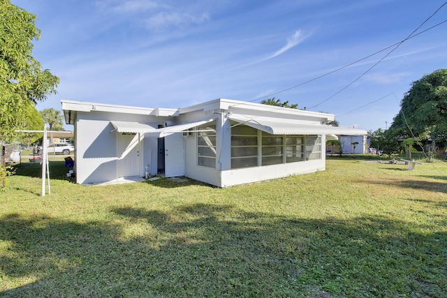 rear view of property with a sunroom and a lawn