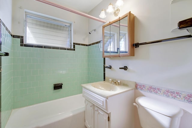 full bathroom with vanity, tiled shower / bath, toilet, and a healthy amount of sunlight